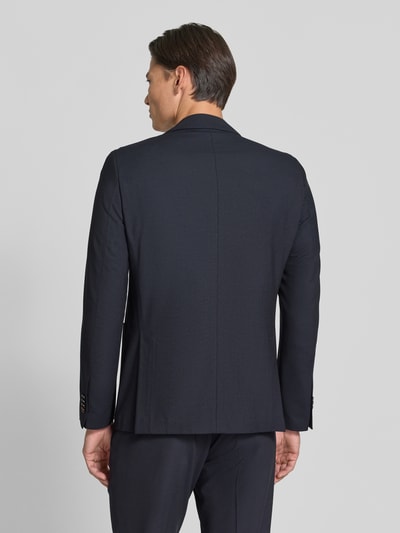 Männermodel trägt Slim Fit 2-Knopf-Sakko aus Schurwoll-Mix von CG – CLUB of GENTS in Dunkelblau mit feiner Textur, Ganzkörperansicht Rückansicht. Kontext: Herren-Sakko Modell 'Carver' mit Reverskragen, aufgesetzten Taschen, Rückenlänge 74 cm, Schulterbreite 46 cm, Ärmellänge 66 cm, Schurwoll-Mix mit Viskose-Anteil.