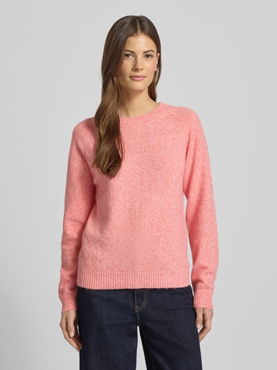 Frauenmodel trägt Regular Fit Strickpullover mit Crew Neck Modell 'DOFFY' von Vero Moda, unifarben rosa, lange Ärmel, gerippte Abschlüsse, Stricktextur, Ganzkörperansicht von vorne.
