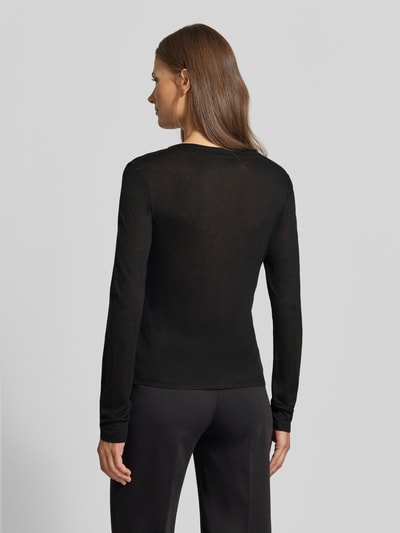 Frauenmodel trägt Longsleeve in semi-transparenter Optik von MYON, schwarz, tailliert, Lyocell-Mix, Rückenansicht, Ganzkörperansicht Rückansicht.
