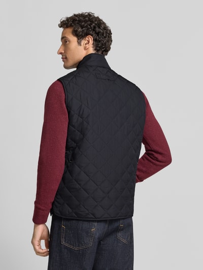 Männermodel trägt Slim Fit Weste mit Logo-Stitching Modell 'NEW LOWERDALE' von Barbour, schwarze Steppstruktur, Ganzkörperansicht Rückansicht. Herren Weste von Barbour.