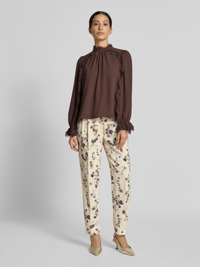 Frauenmodel trägt Regular Fit Bluse mit Spitzenbesatz von Marc Cain in Braun, Chiffon, Stehkragen, lange Ärmel, Ganzkörperansicht von vorne.