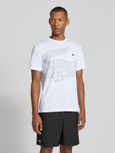 Męski model nosi Regular Fit Sport-T-Shirt aus Baumwoll-Mix von Lacoste, biały z czarnym nadrukiem, prosty krój, widok z przodu, Herren Sport-T-Shirt von Lacoste Sport, Ganzkörperansicht von vorne