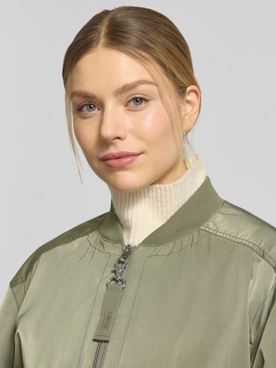 Vrouwenmodel draagt lichte, glanzende olijfgroene dames jack met opstaande kraag, ritssluiting en klepzakken, model 'CIBLOUMINA' van CINQUE, regular fit, ruglengte maat 36: 57 cm, schouderbreedte: 46 cm, borstwijdte: 56 cm, mouwlengte: 58 cm, close-up bovenlichaam