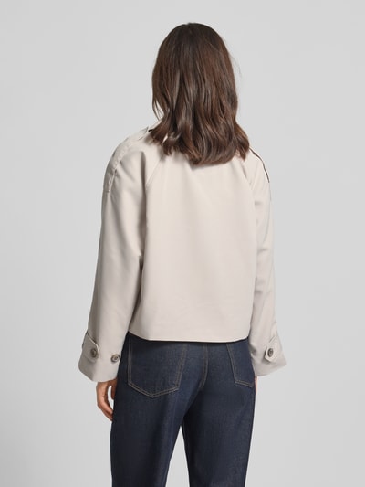 Kobiece modelka ma na sobie Regular Fit Trenchcoat mit Schulterriegeln od Tom Tailor Denim, efekt: jednolity kolor, krój regular fit, kołnierz z połami, zapięcie: listwa guzikowa, detal: guziki, długi rękaw z regulacją na patkę, wpuszczane kieszenie boczne, wykończenie materiału: splot twill; pełen widok sylwetki z tyłu.