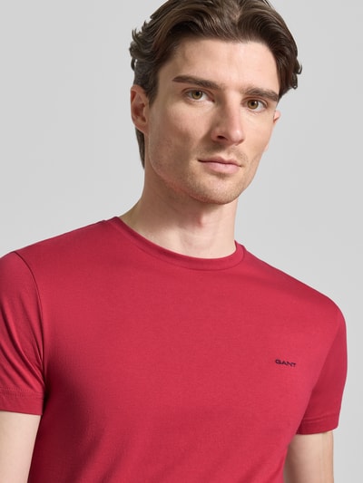 Männermodel trägt t-shirt met labeldetail van Gant in rood, puur katoen, recht model, ronde hals, ruglengte maat M 70 cm, Nahaufnahme Oberkörper.