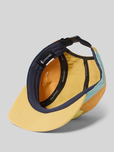Produktfoto, 5-Panel Hat mit Logo-Print Modell 'Tech' von Cotopaxi, bunter Stoff in Gelb, Blau und Orange, sichtbarer Strapback, Logo-Patch