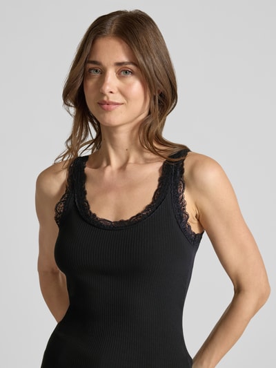 Frauenmodel trägt Slim Fit Tank Top aus Bio-Baumwoll-Mix Modell 'NANA' von Vero Moda, unifarben, Rippstruktur, Spitzenbesatz, Nahaufnahme Oberkörper.