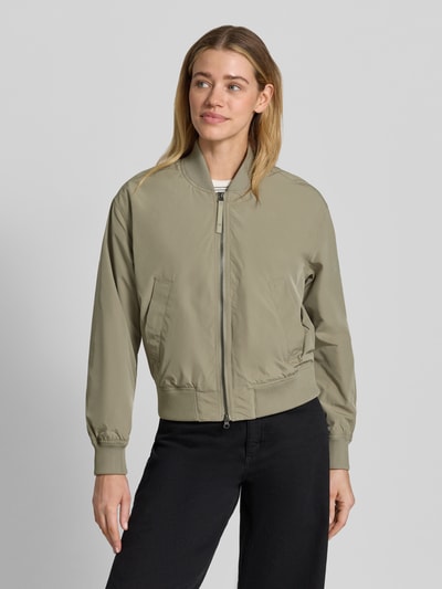 Frauenmodel trägt Regular Fit Jacke mit Stehkragen von camel active in Beige, Zweiwege-Reißverschluss, elastische Abschlüsse, Eingrifftaschen, Ganzkörperansicht von vorne. Rückenlänge 55 cm, Schulterbreite 43 cm, Brustweite 53 cm, Ärmellänge 59 cm.