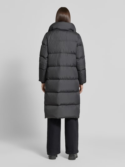 Frauenmodel trägt Regular Fit Daunenmantel mit abnehmbaren Rucksackriemen von Marc O'Polo in dunklem Grau, wattierte Struktur, Ganzkörperansicht Rückansicht. Damen Daunenmantel von Marc O'Polo.