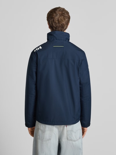 Männermodel trägt Midlayer Jacke mit Stehkragen Modell 'CREW' von Helly Hansen in Dunkelblau, Gerader-Schnitt, Label-Patch, Rückenansicht Ganzkörperansicht.