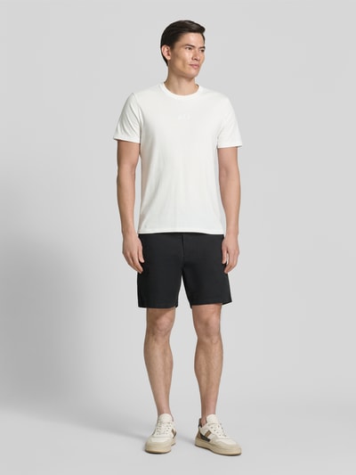 Männermodel trägt T-Shirt mit Rundhalsausschnitt und Label-Stitching von GAP, reine Baumwolle, Regular Fit, weiß, Ganzkörperansicht von vorne.