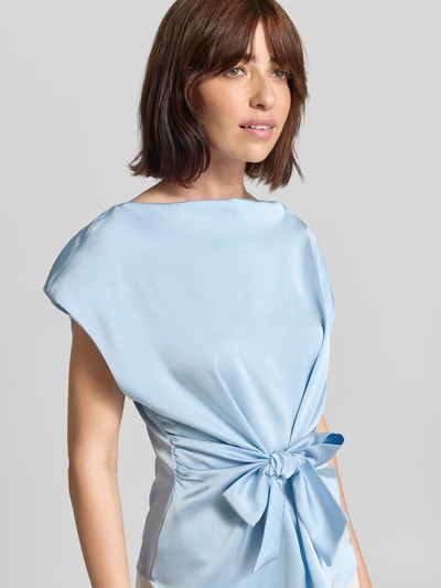 Frauenmodel trägt Blusentop aus Satin mit Schleifen-Detail Modell 'Katarim' von Neo Noir in Hellblau, taillierter Schnitt, Nahaufnahme Oberkörper.