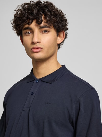 Männermodel trägt Regular Fit Poloshirt aus reiner katoen Modell 'Core' van G-Star Raw in donkerblauw met labeldetail, nahaufnahme oberkörper. Heren poloshirt van puur katoen, polokraag, ruglengte bij maat M 72 cm.