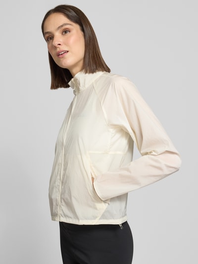 Frauenmodel trägt Regular Fit Jacke mit Stehkragen Modell 'Kout' von Salomon in Creme, Eingrifftaschen, Reißverschluss, Ganzkörperansicht von vorne.