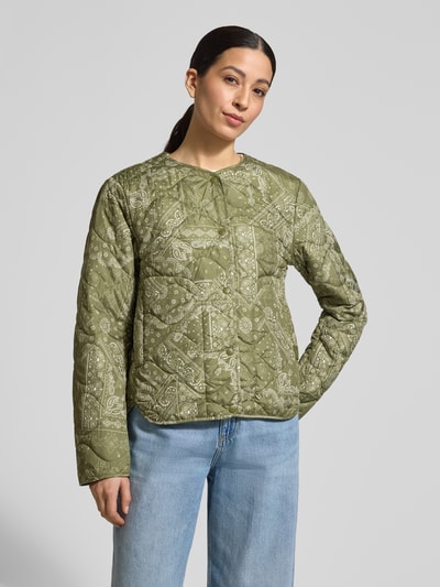 Kobiece modelka nosi Steppjacke mit Rundhalsausschnitt od camel active w kolorze oliwkowym z przeszyciami, krój regular fit, zapięcie na napy, prosta sylwetka, długość tyłu w rozmiarze 36: 60 cm, szerokość ramion w rozmiarze 36: 43 cm, szerokość klatki piersiowej w rozmiarze 36: 53 cm, długość rękawa w rozmiarze 36: 64 cm, całkowity widok z przodu.