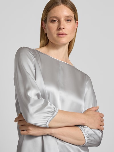 Kobiece model prezentuje Blusenshirt aus Seide mit 3/4-Arm od Marc Cain, kolor srebrnoszary, krój regular fit, okrągły dekolt, długość tyłu 60 cm, długość rękawów 49 cm, jedwab, zbliżenie na górną część ciała.