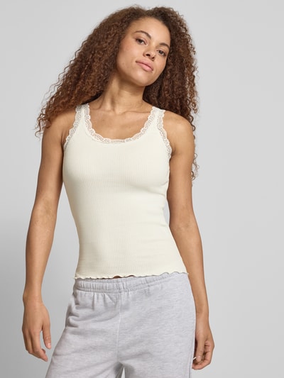 Vrouwenmodel draagt Slim Fit Tank Top uit biologisch katoenmix model 'SARA' van Only, effen crème, fijnrib, kantdetails, U-hals, smalle bandjes, vooraanzicht bovenlichaam.