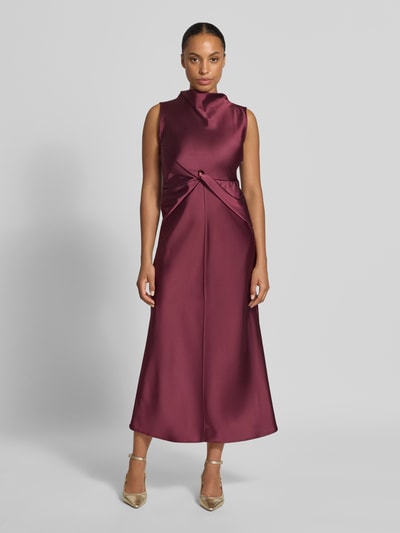 Frauenmodel trägt Cocktailkleid aus Satin mit Raffungen von Rinascimento in Dunkelrot, glänzende Textur, taillierte Passform, Midilänge, ärmellos, Cut Out und rückseitiger Knopfverschluss, Ganzkörperansicht von vorne.