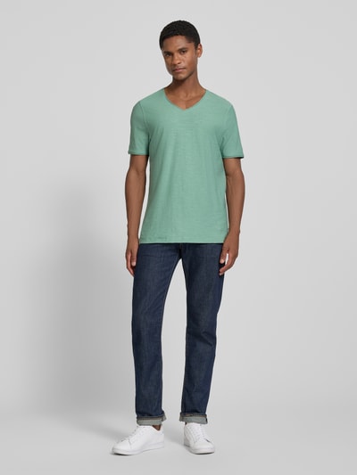 Männermodel trägt T-Shirt mit V-Ausschnitt und Rollsaum von MCNEAL in Grün, Herren T-Shirt aus Reine Baumwolle, Regular-Fit, Ganzkörperansicht von vorne.