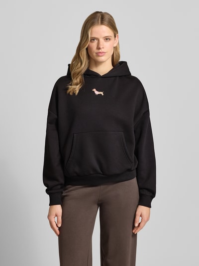Frauenmodel trägt Hoodie mit Motiv-Stitching und Känguru-Tasche von REVIEW aus Baumwoll-Mix, Regular-Fit, schwarze Farbe, Ganzkörperansicht von vorne.