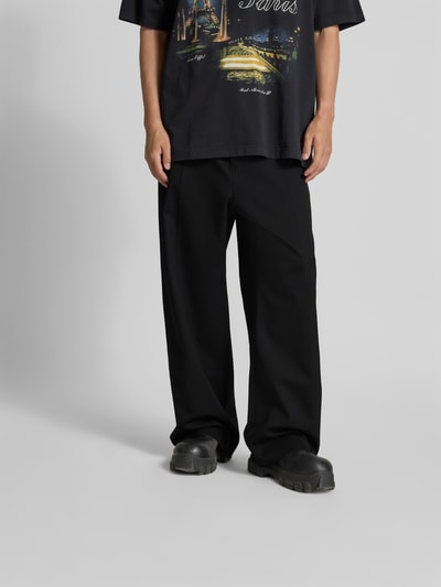 Mężczyznamodel nosi Straight Fit Hose aus Schurwoll-Mix von VETEMENTS, czarny, mieszanka żywej wełny, krój straight fit, kieszenie z tyłu, zakładki w pasie, szerokość w rozmiarze M: 44 cm, długość wewnętrzna nogawki: 77 cm, zapięcie na haftkę i zamek błyskawiczny, spodnie materiałowe, widok całej sylwetki z przodu