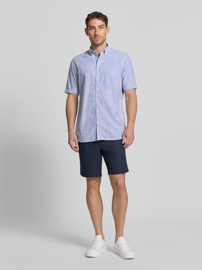 Męski model nosi Regular Fit Freizeithemd mit Brusttasche od Christian Berg Men, bawełna, kołnierzyk typu button down, krótki rękaw, listwa guzikowa, niebieskie paski, całkowity widok z przodu. Długość tyłu w rozmiarze M: 79 cm, szerokość w rozmiarze M: 47 cm, długość rękawów w rozmiarze M: 26 cm.