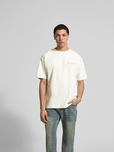 Männermodel trägt Regular Fit T-Shirt aus Baumwoll-Mix von Don't Waste Culture, cremefarben mit Statement-Print, Kurzärmelig, Ganzkörperansicht von vorne. Rückenlänge bei Größe M: 70 cm.