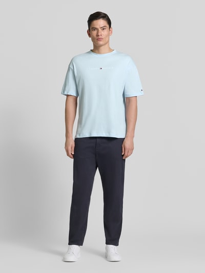 Męski model nosi Regular Fit T-Shirt mit Label-Schriftzug aus reiner Baumwolle von Tommy Hilfiger, jednolity, krój regular fit, krótki rękaw, okrągły dekolt, czysta bawełna, przód całej sylwetki.