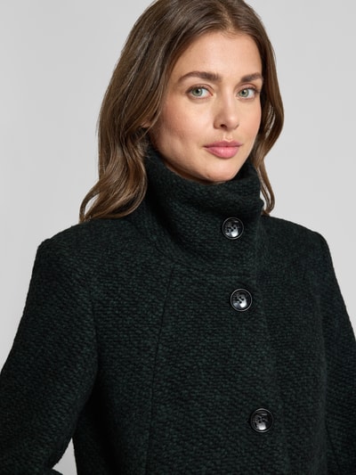 Kobiece model nosi płaszcz z mieszanki materiałów z dodatkiem żywej wełny, stójka, fakturowany wzór, zapięcie na guzik, wpuszczane kieszenie, Model 'LISETTE' od Milo Coats, krój slim fit, zbliżenie górnej części ciała.