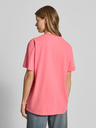 Frauenmodel trägt T-Shirt mit Statement-Print und Rundhalsausschnitt von OH APRIL in Pink, Oversized, Reine Baumwolle, Rückenlänge 70 cm, Ganzkörperansicht Rückansicht.
