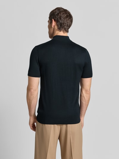 Männermodel trägt Strickshirt aus Viskose-Mix mit Stehkragen Modell 'Vadin' von JOOP! in Schwarz, feine Textur, Ganzkörperansicht Rückansicht. Körpernaher Schnitt, kurze Ärmel, kurzer Reißverschluss, Rückenlänge 68 cm, Ärmellänge 24 cm.