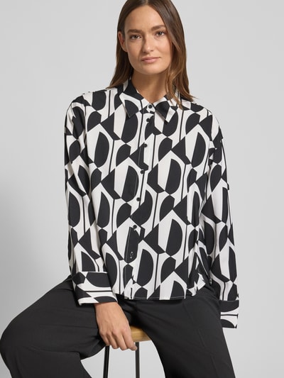 Vrouwenmodel draagt Hemdbluse aus Viskose-Mix met Hemdblusenkragen Modell 'Fetro' van OPUS, relaxed fit, zwart-witte geometrische allover-print, lange mouwen, volledige knoopsluiting, sportmanchetten, vooraanzicht bovenlichaam.