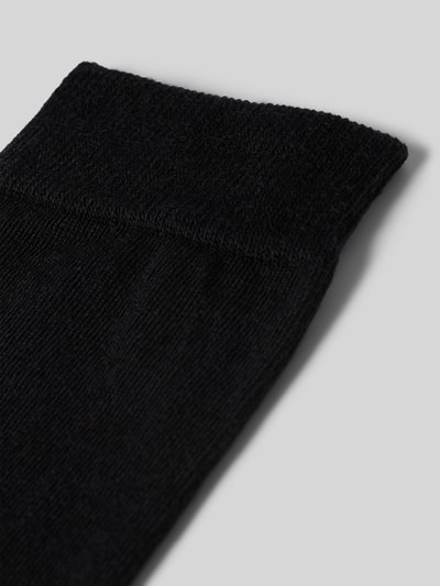 Produktfoto, czarne Socken mit Label-Schriftzug Modell 'SOFTMERINO' von FALKE z mieszanki wełny i bawełny z elastycznym ściągaczem, tekstura miękka.