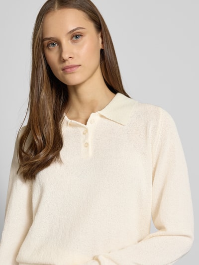 Frauenmodel trägt Langärmliger Polo-Strickpullover aus Bouclé-Garn von Review, cremefarben, Strick-Optik, lockere Passform, Nahaufnahme Oberkörper.