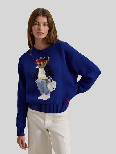 Frauenmodel trägt Regular Fit Strickpullover mit Polo-Bear-Intarsia von Polo Ralph Lauren, unifarbenes Blau, reine Baumwolle, Ganzkörperansicht von vorne.