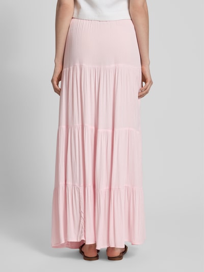 Frauenmodel trägt Maxirock im Stufen-Look von REVIEW aus reiner Viskose in zartem Rosa, A-Linie, mit Tunnelzug, Ganzkörperansicht Rückansicht.