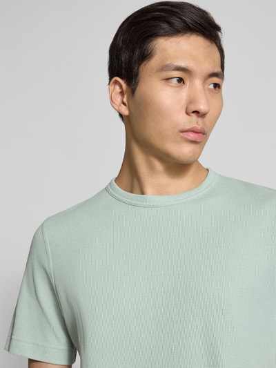 Männermodel trägt Regular Fit T-Shirt aus Baumwoll-Mix von Tom Tailor, Optik: Unifarben, Label-Patch, Piqué-Struktur, Nahaufnahme Oberkörper.