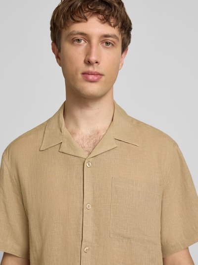 Männermodel trägt Relaxed Fit Freizeithemd aus Leinen-Viskose-Mix Modell 'LAURENCE' von Only & Sons, Optik: Unifarben, Reverskragen, einreihige Knopfleiste, Kurzarm, Brusttasche, sandfarbene Struktur, Nahaufnahme Oberkörper.