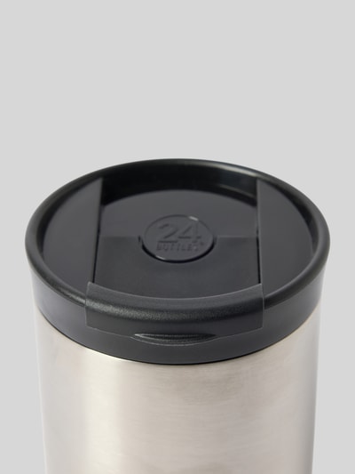 Produktfoto, Becher aus Edelstahl mit Logo von 24bottles, silberfarbene Oberfläche, schwarzer Deckel mit Trinköffnung, Nahaufnahme.