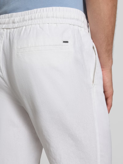 Männermodel trägt Tapered Leinenhose aus Baumwoll-Leinen-Mix Modell 'LINUS' von Only & Sons, melierte Optik, Nahaufnahme Rückansicht.
