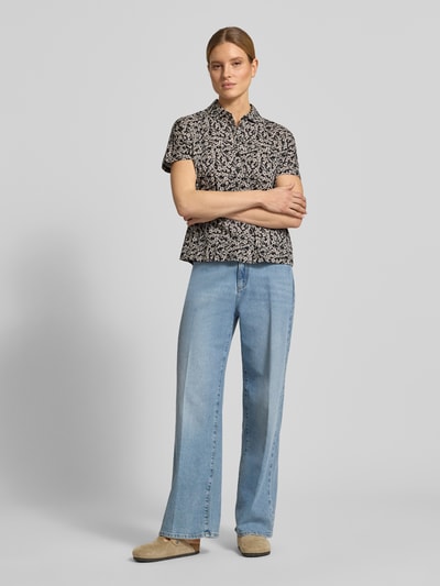 Frauenmodel trägt Relaxed Fit Poloshirt aus reiner Baumwolle von Marc O'Polo, Optik:Allover-Muster, Muster: floral, Polokragen, V-Ausschnitt, kurze Knopfleiste, Ärmelform: Kurzarm, Materialverarbeitung: Jersey, Farbe schwarz mit hellem floralen Print, Kombi mit heller Jeans und beigefarbenen Schuhen, Ganzkörperansicht von vorne