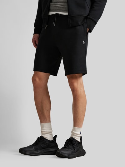 Männermodel trägt Regular Fit Sweatshorts aus Baumwoll-Mix von Polo Ralph Lauren, unifarben schwarz, Logo-Stitching, Nahaufnahme Unterkörper.