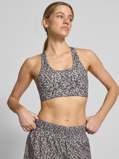 Frauenmodel trägt Freesoft Sport-BH mit Racerback Modell 'selma' von VARLEY im Material-Mix mit Stretch-Anteil und Rundhalsausschnitt, mit Logo-Print, Nahaufnahme Oberkörper.