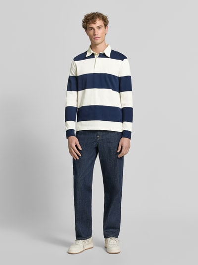 Männermodel trägt Poloshirt aus reiner Baumwolle von Christian Berg Men mit breiten blauen und weißen Streifen, lockere Passform, Ganzkörperansicht von vorne.