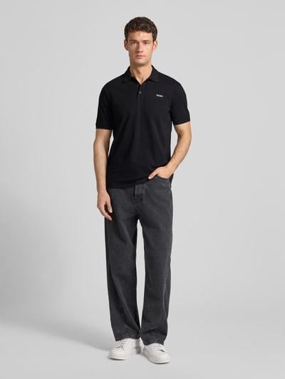 Männermodel trägt Regular Fit Poloshirt aus reiner Baumwolle Modell 'DONOS222' von HUGO, Optik: Unifarben, Ganzkörperansicht von vorne.