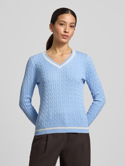 Modelka kobieca nosi Slim Fit Longsleeve in Strick-Optik od Christian Berg Woman w jasnoniebieskim kolorze, bawełniany miks, krój slim fit, tekstura dzianiny, dekolt V, elastyczne wykończenia, długość tyłu w rozmiarze S: 58 cm, długość rękawa w rozmiarze S: 63 cm. Widok całej sylwetki z przodu.