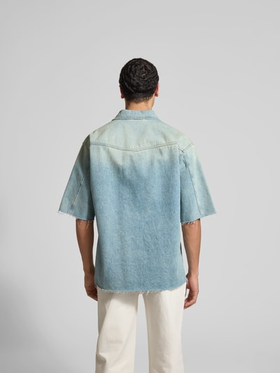 Männermodel trägt Relaxed Fit Jeanshemd mit Logo-Stitching von MM6 Maison Margiela in Hellblau, reine Baumwolle, Rückenansicht Ganzkörperansicht.