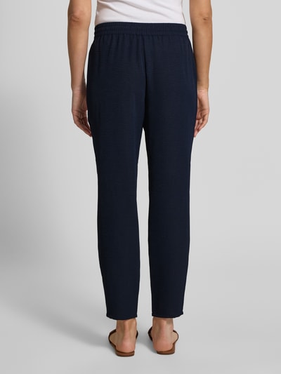 Frauenmodel trägt Jogpants mit elastischem Bund und Eingrifftaschen von Christian Berg Woman in Dunkelblau, Ganzkörperansicht Rückansicht. Slim Fit, Kordelzug, Französische Eingrifftaschen, Bundweite bei Größe 36: 38 cm, Innenbeinlänge bei Größe 36: 72 cm.