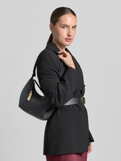Frauenmodel trägt Shoulder Bag aus echtem Leder mit Logo-Detail Modell 'Goccia' von FURLA in Schwarz, matte Strukturen, Ganzkörperansicht von vorne. Hauptfach mit Reißverschluss und Schulterriemen, Maße ca. 22x23x7 cm, Riemenlänge 56 cm.