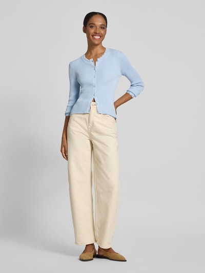 Frauenmodel trägt Slim Fit Strickjacke aus Viskose-Mix Modell 'Wonder' von Vero Moda, Optik: Unifarben, Rippstrick, Applikation: Spitzen-Besatz, Rundhals, Langarm, Materialverarbeitung: Viskose-Mix, hellblaue Farbe, feine Textur, Ganzkörperansicht von vorne.